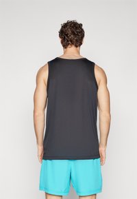 Débardeur noir sans manches en tissu lisse, associé à un short bleu clair. Il présente une coupe décontractée et un col arrondi.