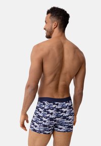 Marinblå kamouflageprint boxer-sjorts med en slät textur och elastisk midja, sedd bakifrån.