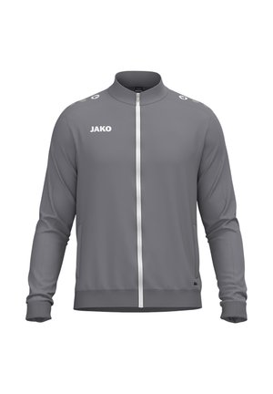 Veste de sport grise zippée intégralement, col montant, poignets élastiques, poches latérales et logo JAKO blanc sur la poitrine et les épaules.