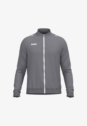 Giacca sportiva grigia con zip lunga, collo alto, polsini elastici, tasche laterali e logo JAKO bianco sul petto e sulle spalle.