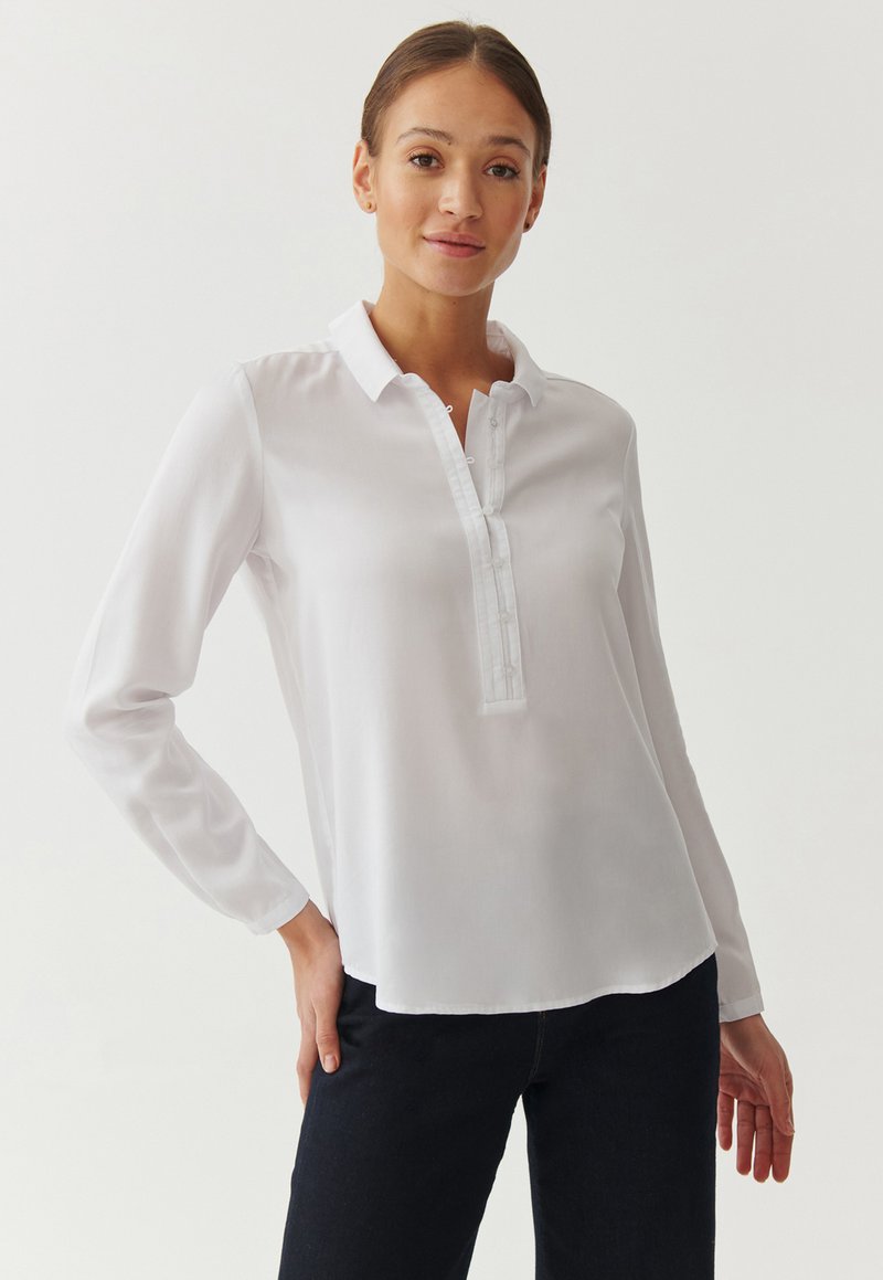 Witte blouse met lange mouwen, voorzien van een spitse kraag, knopenlijst en een gladde textuur. Het heeft een losse pasvorm en een gebogen zoom.
