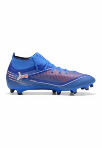 Crampons de football bleus avec un upper en synthétique texturé, présentant des rayures orange dégradé, un design à ajustement serré et des crampons noirs pour une meilleure traction.