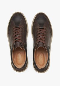 Brązowe skórzane trampki o teksturowanej powierzchni, z kontrastującą ciemną osłoną palców, sznurowanym zapięciem i jasnobeżowym wnętrzem. Gumowa podeszwa z subtelnymi akcentami.