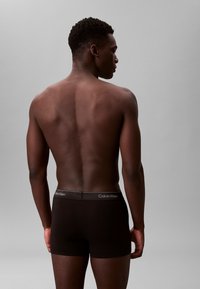 Schwarze Baumwollboxershorts mit einem Calvin Klein Logo-Bund, der ein eng anliegendes Design zeigt. Das Modell wird von hinten betrachtet.