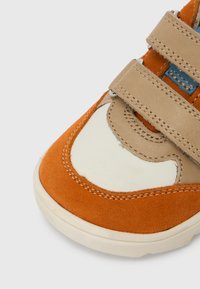 Baskets multicolores en suède orange et cuir beige, avec un bout en caoutchouc blanc. Comprend deux bandes Velcro et une couture contrastante.