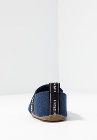 Námořnické plstěné pantofle s texturovaným svrchním materiálem, vybavené černobílou značenou patkou a flexibilní gumovou podrážkou.