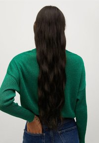 Vihreä ribbineulottu neuletakki, jossa väljä istuvuus, pitkät hihat ja leveä pääntie. Yhdistetty korkeavyötäröiseen siniseen farkkuun.