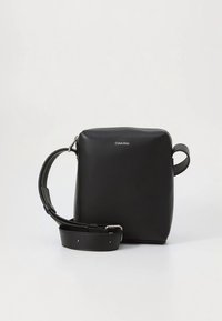 Black leather crossbody bag with a square shape, featuring a silver logo, adjustable strap, and smooth texture. Minimalist design.