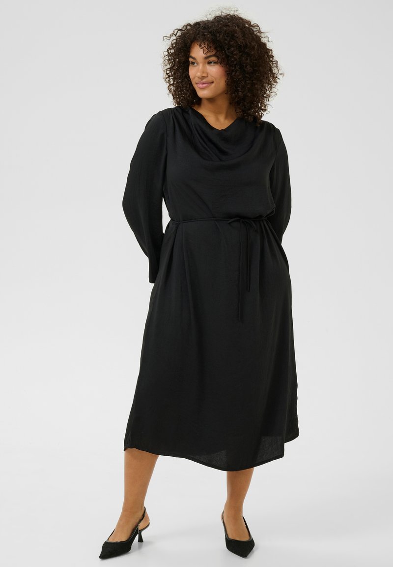 Vestido midi negro con escote drapeado, mangas largas y cintura con lazo. Textura suave, tejido fluido y corte recto hasta el dobladillo.