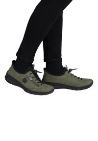 Sneakers in suede verde con dettagli neri, dotati di una chiusura con zip, lacci e una suola in gomma nera strutturata.