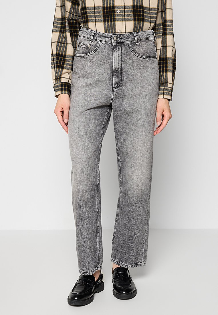 Szare dżinsy denimu o prostym kroju nogawek, z pięcioma kieszeniami i lekko wybledzonym wykończeniem. Noszone z czarną i beżową koszulą w kratę.
