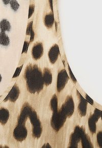 Leopardprint camisole med en beige baggrund, prydet med mørkebrune og sorte pletter. Glat tekstur med en rund halsudskæring og syede kanter.