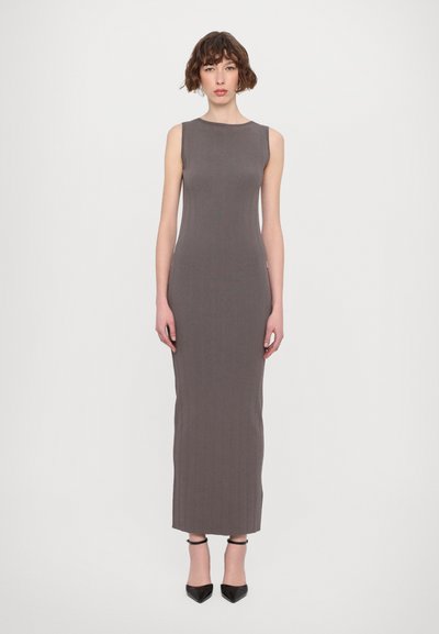 Robe sans manches, longue jusqu'au sol, en tissu côtelé gris, avec un décolleté rond et une silhouette ajustée, complétée par des escarpins noirs.