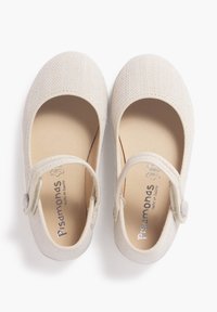 Chaussures pour enfants couleur beige clair avec une tige en tissu texturé, bout arrondi et une sangle avec fermeture à bouton. Doublure intérieure douce.