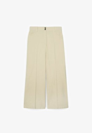 Pantalons beige à jambes larges avec deux poches frontales, double boutons à l'avant, et un tissu lisse et texturé. Taille plate et design ajusté.