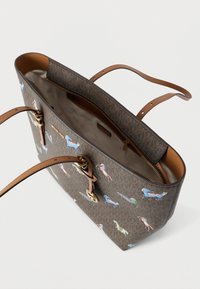 Καφέ τσάντα tote με ταμπά λαβές, διακοσμημένη με πολύχρωμα άλογα, ανοιχτό πάνω μέρος που αποκαλύπτει μπεζ εσωτερικό και τσεπάκι με φερμουάρ.