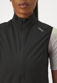 Gilet de cyclisme noir sans manches avec col haut, fermeture éclair sur le devant et tissu texturé. Présente le logo Giro sur l'épaule.
