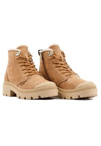 Bottines en cuir marron clair avec doublure en fourrure crème, devant à lacets et fermeture éclair latérale. Semelle en caoutchouc beige épaisse avec prise texturée.