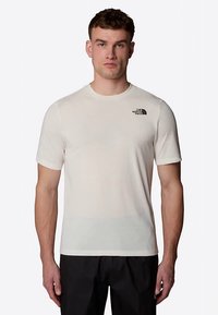 Lichtbeige T-shirt met korte mouwen gemaakt van stof met een gladde textuur. Voorzien van een klein zwart logo op het linkerborstgebied. Standaard pasvorm.