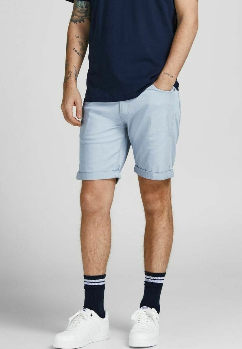 Světle modré šortky s ohrnutými manžetami, nošeny s námořnickým tričkem. Součástí outfitu jsou bílé tenisky a černé ponožky s bílými pruhy.