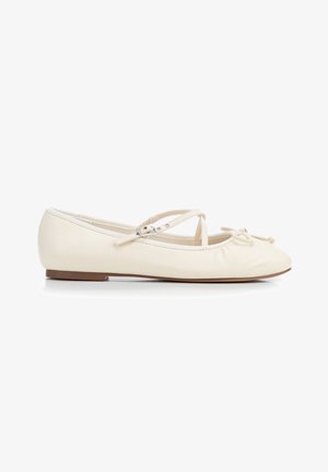 Ballerina in pelle color crema con punta arrotondata, cinturini incrociati alla caviglia, piccolo fiocco sul davanti e suola piatta.