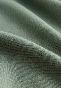 Weiches, strukturiertes Gewebe in einem gedämpften Grünton, mit einem gewebten Muster, sichtbaren Fasern und leichtem Glanz. Ideal für Bekleidung oder Polsterung.