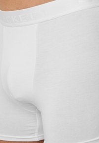 Boxers ajustés en coton blanc mélangé avec une texture lisse, un design ajusté et une taille élastique douce comportant un branding subtil.