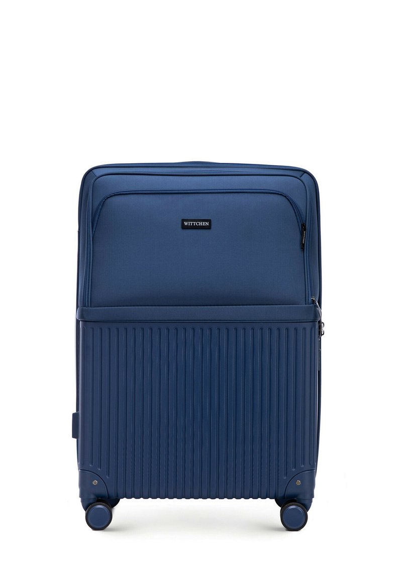 Valise rigide bleu marine avec des rainures verticales, roues doubles, compartiments zippés et une poche avant. Logo de la marque visible à l'avant.