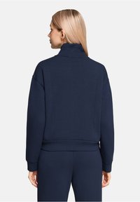 Navy blue sweatshirt with a high collar, dropped shoulders, and a relaxed fit. Soft, textured fabric; ribbed cuffs and hem detail.