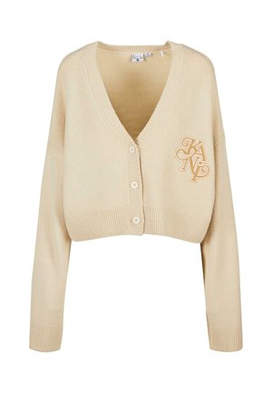Puha kötött anyagból készült bézs cropped kardigán. Mély V-nyakkal, hosszú ujjal, bordázott szegélyekkel és bal oldalon hímzett logóval rendelkezik.