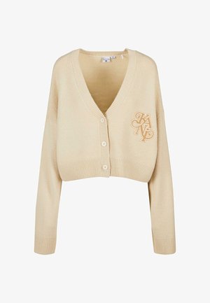 Beżowy krótki kardigan wykonany z miękkiej dzianiny. Posiada głęboki dekolt w kształcie V, długie rękawy, prążkowane wykończenia i haftowane logo po lewej stronie.