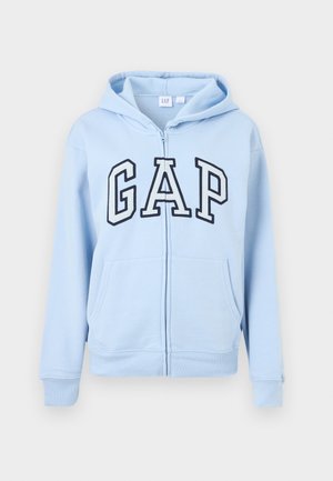 Lichtblauwe hoodie met ritssluiting, voorzakken en een groot "GAP"-logo in wit en marineblauw op de borst, met capuchon.