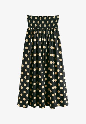 Black strapless dress with gathered waist and large beige polka dots covering the full length of the skirt.