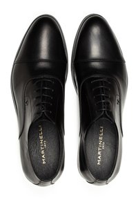 Un par de zapatos de vestir para hombre de cuero negro pulido con cordones y "Martinelli 1973" impreso en dorado en el interior.