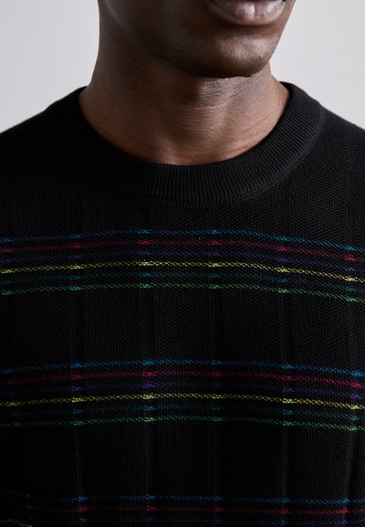 Pull en tricot noir avec une finition texturée, ornée de rayures horizontales colorées en bleu, rouge, vert et jaune au niveau de la poitrine.