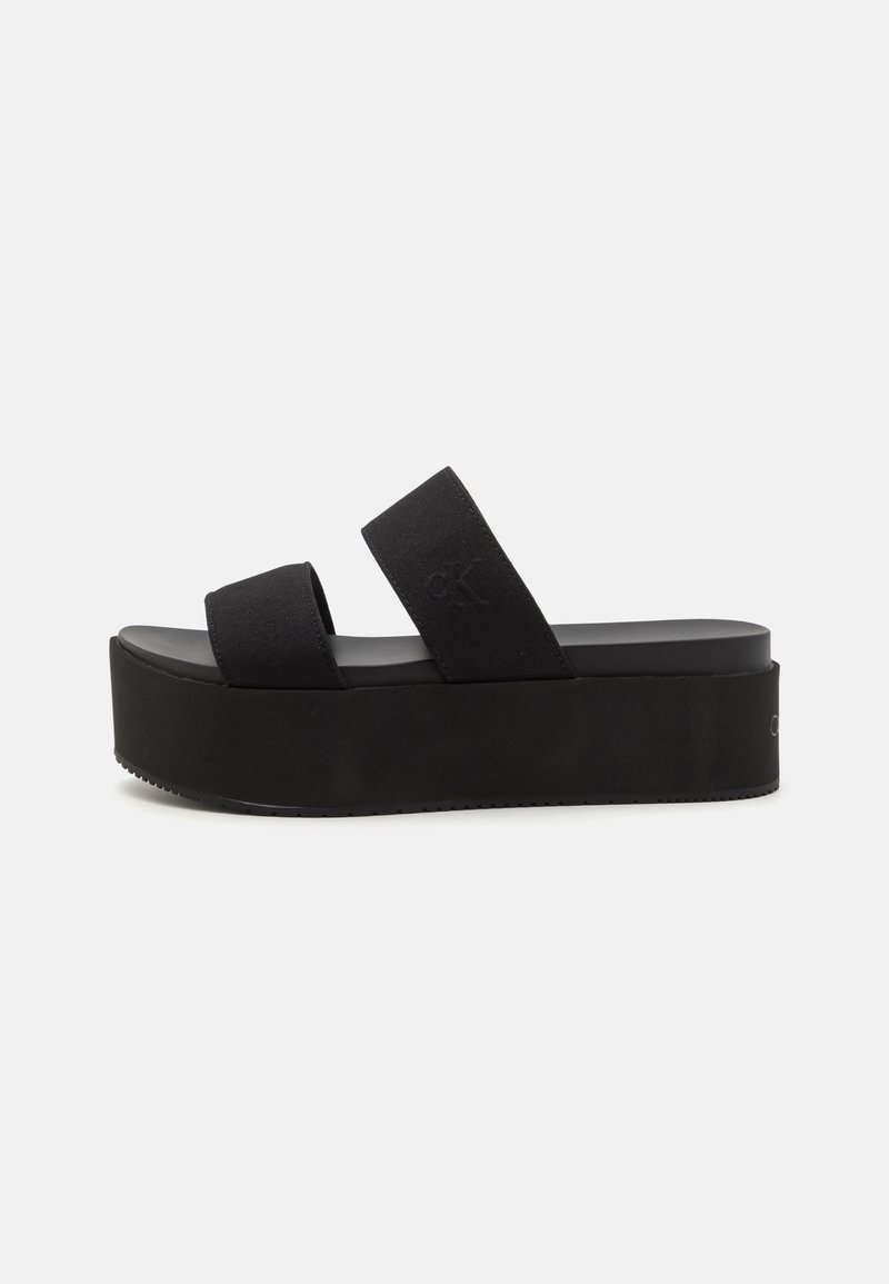 Black platform sandals featuring dual wide fabric straps and a thick rubber sole for enhanced height and comfort. Simple design with no patterns.