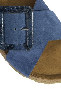 Sandale en daim bleu avec une boucle rectangulaire texturée de couleur bleu marine et une semelle intérieure douce couleur tan. Le design comprend des brides croisées pour un bon maintien.