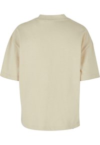 Camiseta corta de manga corta en color beige, hecha de una tela suave, con un corte relajado y un escote redondeado. Sin patrones ni acentos visibles.