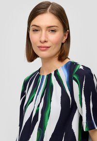 T-shirt à manches courtes avec une base bleu marine et des rayures abstraites vertes et bleues. Fabriqué dans un tissu léger à texture douce et avec un col rond.