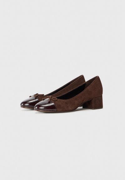 Pumps à talons blocs en daim marron avec un bout en crocodile brillant de couleur marron foncé, ornés d'un accent en nœud à l'avant.