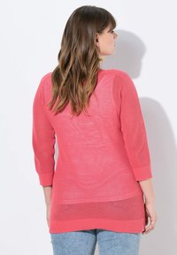 Jersey de punto coral con mangas tres cuartos, que presenta un diseño texturizado y acentos acanalados en los puños y el dobladillo.