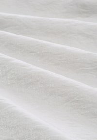 White fabric with a soft, smooth texture and subtle sheen, draped in folds, showcasing light and shadow variations.