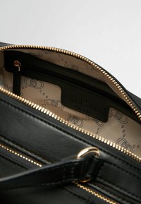 Borsa a mano in pelle nera con zip e dettagli dorati. L'interno presenta una fodera beige con un motivo a logo ripetuto e una tasca con cerniera.