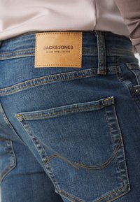Denim-Jeans mit einem Leder-Logo-Patch mit der Aufschrift "JACK & JONES", gelben Nähten, klassischem Schnitt und Gesäßtaschen mit gebogenen Nähten.