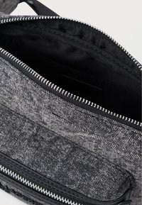Šedá textilná taška zvnútra so zipsom, s hladkým čiernym podšívkovým materiálom a viditeľným šitím. Minimalistický dizajn s kontrastnými textúrami.