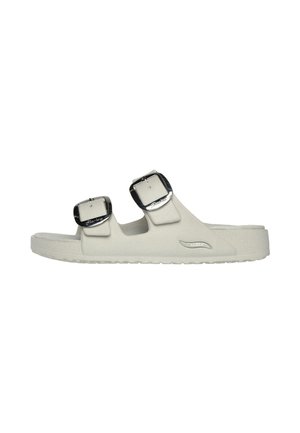 Infradito bianche realizzate in materiale liscio con due fibbie nere regolabili e una suola testurizzata. Design semplice con un profilo minimale.