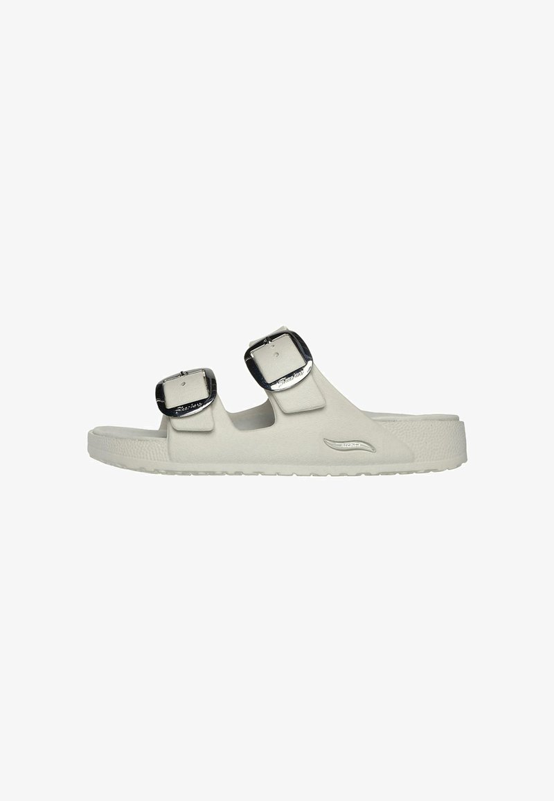 White slide sandals made from smooth material with two adjustable black buckles and a textured sole. Simple design with a minimal profile.