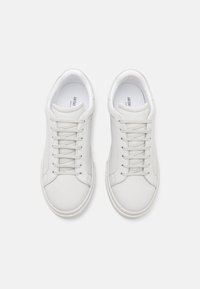 Zapatillas de cuero blancas con punta redonda, diseño con cordones, costuras detalladas y suela de goma texturizada. El interior cuenta con etiqueta de marca.