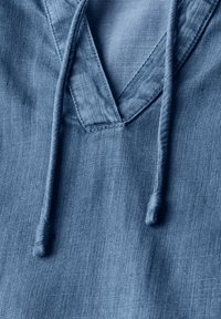 Felpa con cappuccio in denim di colore azzurro chiaro, caratterizzata da un design a V, cordini e una finitura testurizzata. Tessuto liscio con variazioni di colore sottili.