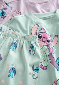 Tre plagg med lekfulla Stitch-mönster. Mjuk bomull i lila och mintgrön. Mintmönstret visar prickar och upprepade karaktärsillustrationer.
